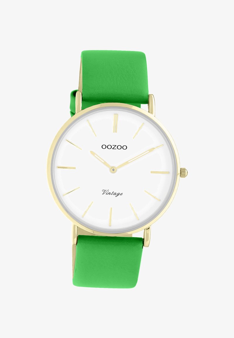 Cadran de montre rond blanc avec marqueurs et aiguilles dorés, bracelet en cuir vert, nom de la marque OOZOO, et texte "Vintage" sur le cadran.