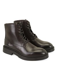 Bottes chevilles en cuir marron avec une finition lisse, bout rond, laçage avant et œillets en métal ; dotées d'une semelle en caoutchouc épaisse et texturée.