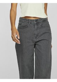 Vysoké, volné černé džíny z denimu s jemnou texturou, předními kapsami a zapínáním na knoflík, spárované s lehkým zkráceným topem.