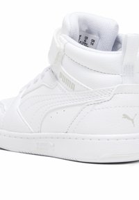 Weiße Hohe-Sneaker aus strukturiertem Kunstleder. Verfügt über einen gepolsterten Kragen, eine Schnürung vorne und einen Klettverschluss. Puma-Logo sichtbar.