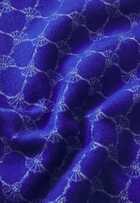 Tessuto viola con una texture morbida, caratterizzato da un motivo geometrico di cerchi interconnessi e accenti simili a stelle in tonalità più chiare.