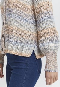 Stickad cardigan med flerfärgade ränder i kräm, orange och blått. Har träknappar, ribbade ärmslut och sidofickor för ökad komfort.