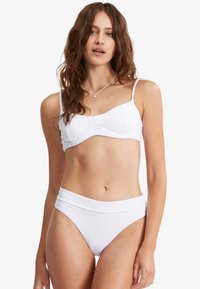 Bílý žebrový bikiny top s nastavovacími ramínky a odpovídajícími bikiny kalhotkami s vysokým pasem, které mají hladkou strukturu a jemné detaily švů.