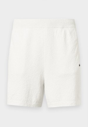 Pantalones cortos blancos y texturizados con una cintura acanalada. Tienen un corte holgado y un pequeño detalle de logo en el lado inferior.