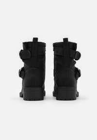 Botines negros hechos de cuero sintético texturizado con correas ajustables y herrajes de plata, con un tacón bloque y cremalleras laterales.
