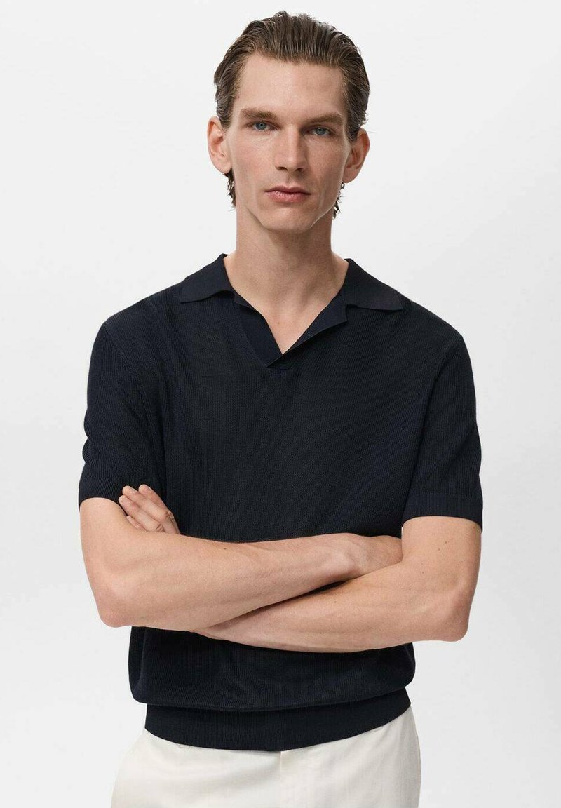 Polo de punto de manga corta en marino oscuro. Presenta un collar plano y textura acanalada. Puños ajustables y silueta entallada.