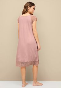 Chemise rosa con una vestibilità ampia, maniche a cappuccio in pizzo e orlo con rifinitura in pizzo, caratterizzata da una consistenza liscia e un design che arriva fino al ginocchio.