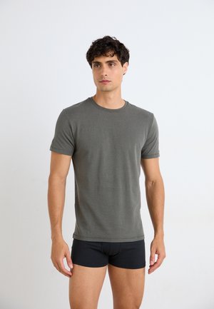 Gray short-sleeve t-shirt made of cotton blend fabric. Simple round neckline, fitted shape, smooth texture. Worn with black boxer shorts.