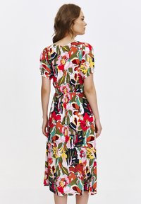 Kolorowa sukienka w kwiaty z bufkami, z wcięciem w talii i długością do kolan. Posiada żywy wzór w odcieniach czerwieni, różu, zieleni i żółci.