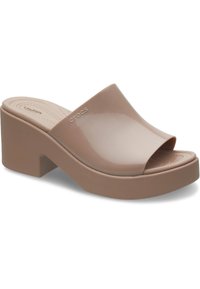 Infradito Crocs beige con superficie lucida, design open toe e un tacco chunky. Suola testurizzata per un comfort aggiuntivo.