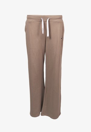 Pantalon de survêtement beige à jambes larges avec taille resserrée par un cordon blanc et petit emblème noir en forme de cœur sur la hanche droite.