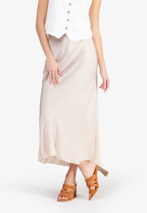 Beige satijnen maxi-rok met een iets uitlopende zoom, gecombineerd met bruine sandaaltjes met hakken met een vierkante hak en een open teen ontwerp.