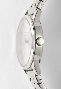 Orologio in acciaio inossidabile argento con quadrante bianco, cassa rotonda sottile e corona texturizzata, dotato di bracciale lucido e design minimalista.