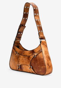 Bolso de hombro de cuero marrón con forma curva, tachuelas metálicas en la correa y un acabado texturizado, que presenta un acento de diseño único.