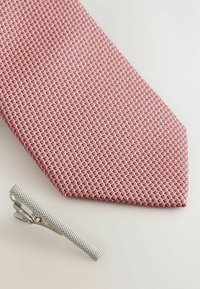 Texturierte pinkfarbene Krawatte mit einem Rautenmuster, kombiniert mit einer silbernen Krawattennadel mit einem diagonalen Texturmuster.