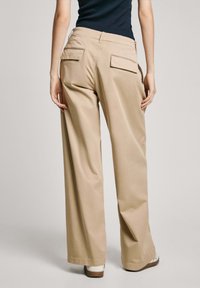 Pantalons beige à jambe large en tissu lisse, dotés de deux poches arrière, avec une taille ajustée et une silhouette décontractée et fluide.