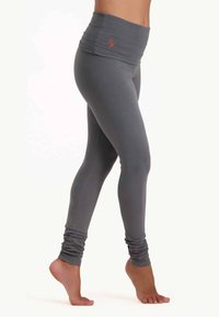 Grå höga leggings med smal passform, tillverkade av elastisk tyg; har samlade benslut och en liten logotyp i orange.