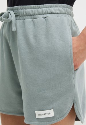 Jasnozielone szorty z elastycznym pasem i sznurkiem, boczną kieszenią, zakrzywionym brzegiem oraz metką Marc O’Polo na przedniej, dolnej części nogawki.