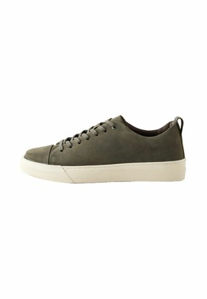 Gray leather sneaker with a rounded toe, flat white rubber sole, and lace-up design. Features a small pull tab at the heel for easy wear.