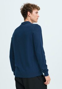 Suéter de punto azul marino con mangas largas, cuello y puños acanalados, con un dobladillo recto y textura suave.