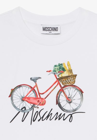 Camiseta blanca con una ilustración colorida de una bicicleta roja con una cesta que contiene hojas verdes y pan, junto al nombre de la marca "Moschino."