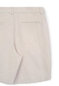 Shorts in lino beige con taglio dritto, dotati di due tasche posteriori e cuciture pulite. Il tessuto ha un aspetto naturale e testurizzato.