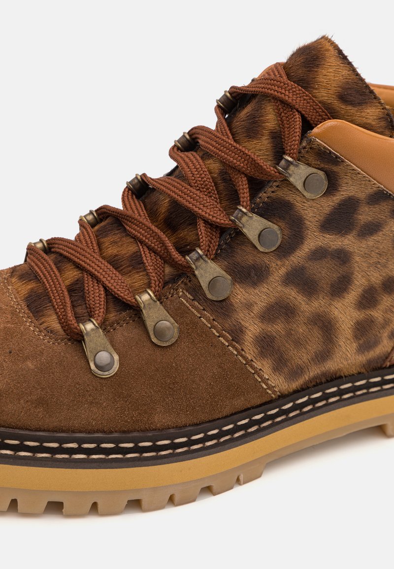 Chaussure de randonnée en daim brun avec des accents en imprimé léopard, dotée de lacets bruns, d'œillets en laiton et d'une semelle en caoutchouc robuste.