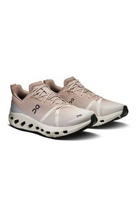 Leichte Laufschuhe in Beige und Weiß, mit einem Obermaterial aus Netzgewebe, gepolsterter Sohle mit Aussparungen und schwarzen Gummi-Akzenten.