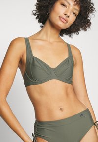 Olivengrønn bikinitopp med strukturert underwire-bh med brede stropper og høyt liv-bunn med justerbare snorer. Glatt tekstur.