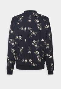 Veste noire à manches longues avec poignets et ourlet côtelés, présentant un motif dispersé de petites fleurs blanches et rose clair avec des feuilles vertes.