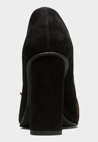 Černá semišová vysok á bota na podpatku s masivním podpatkem, kulatou špičkou a jemným prošíváním po zadní části a bocích. Hladká vnitřní podšívka.