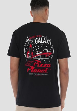 Person trägt ein schwarzes T-Shirt mit rotem und weißem "Pizza Planet"-Weltraum-Logo und dem Slogan "Frischste in der Galaxie" auf der Rückseite.