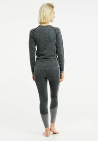 Grauer Sportoberteil und Leggings aus strukturiertem Stoff, mit taillierter Passform und kontrastierenden Akzenten an den Ärmeln und Unterschenkeln.