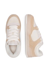 A bézs és fehér sportcipők bőrből és velúrból készültek, kerek orrúak, fűzős kialakításúak, és texturált díszítések találhatók az oldalakon.