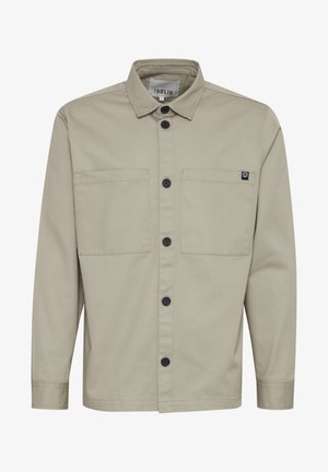 Chemise à boutons en tissu léger khaki, avec deux poches avant, boutons noirs et un petit écusson sur le côté gauche. Design de col classique.