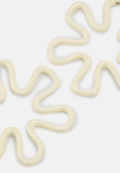 Wellig, cremefarbener Kunststoffkettenlink mit einer glatten, glänzenden Oberfläche und unregelmäßigen Kurven sowie variierenden Breiten im gesamten Design.