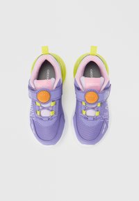 Zapatillas deportivas moradas para niños con parte superior de malla, con un cuello rosa y una suela exterior translúcida verde, sujetas por una correa de Velcro.