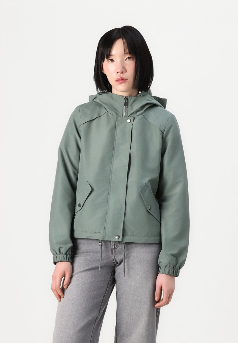 Green waterproof jacket with a hood, zip closure, and elastic cuffs. Features two side pockets and a relaxed fit design.