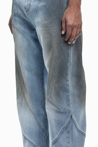 Lichtblauwe denim jeans met een vervaagd textuur, hoekig naaddesign en lichte slijtage. Zijzakken zijn zichtbaar.
