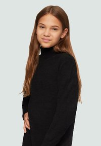 Zwarte turtleneck trui met een zachte, gestructureerde afwerking en lange mouwen, gedragen door een persoon met stijlvol, lang haar.