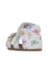 Hvide sandaler med flerfarvede sommerfuglemønstre, åbne sider, velcrolukning og tekstureret indersål. Flad sål med subtilt greb.