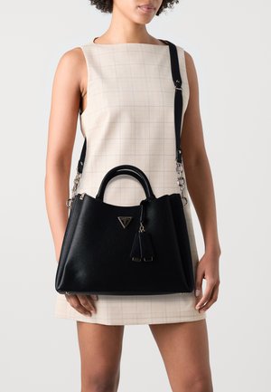 Borsa a tracolla in pelle nera con una forma strutturata, doppi manici superiori, tracolla removibile e un logo triangolare con due decorazioni a frange.