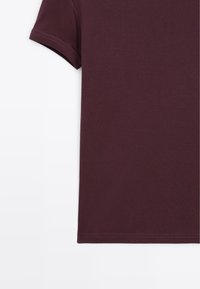 Korte mouwen, donker bordeaux katoenen T-shirt op een witte achtergrond, waarbij de bovenste linkerkant en de details van de mouw worden weergegeven.