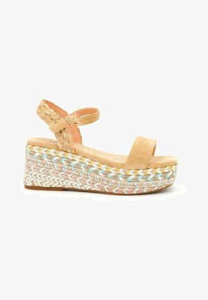 Sandales en suède beige à plateforme avec une sangle cheville tressée, talon en coin présentant une texture tissée et des couleurs pastel dans un motif en zigzag.