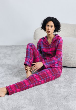 Rutete pyjamasett i rosa, rød og blå farger. Løs passform på toppen med knapper og matchende bukser. Myk, teksturert stoff.