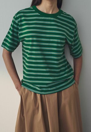 T-shirt à rayures vertes avec manches courtes, présentant des rayures horizontales blanches et bleues ; tissu en coton doux ; col rond ; coupe décontractée.