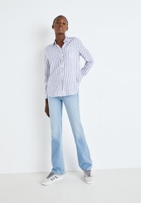 Striped button-up skjorte i lyseblått og hvitt, laget av bomull, med en brystlomme og lange ermer, sammen med lysvaskede utsilhuettjeans.