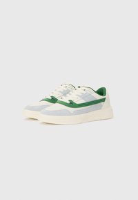 Sport sneakers med en overdel i lys blå og hvid suede med grønne detaljer, teksturerede perforeringer og en tyk flødefarvet sål.