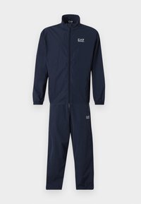 Tuta navy realizzata in materiale leggero, dotata di giacca con zip e colletto, con polsini elasticizzati, e pantaloni abbinati con dettagli del logo.