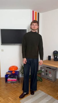 Tumma vihreä ribbireunallinen poolopaita yhdistettynä löysiin tummiin farkkuciin ja kiiltäviin tummaan kenkiin; seisoo modernissa sisätilassa.